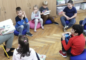 Dzieci siedzą w kręgu i słuchają czytanej poezji o tematyce jesiennej.